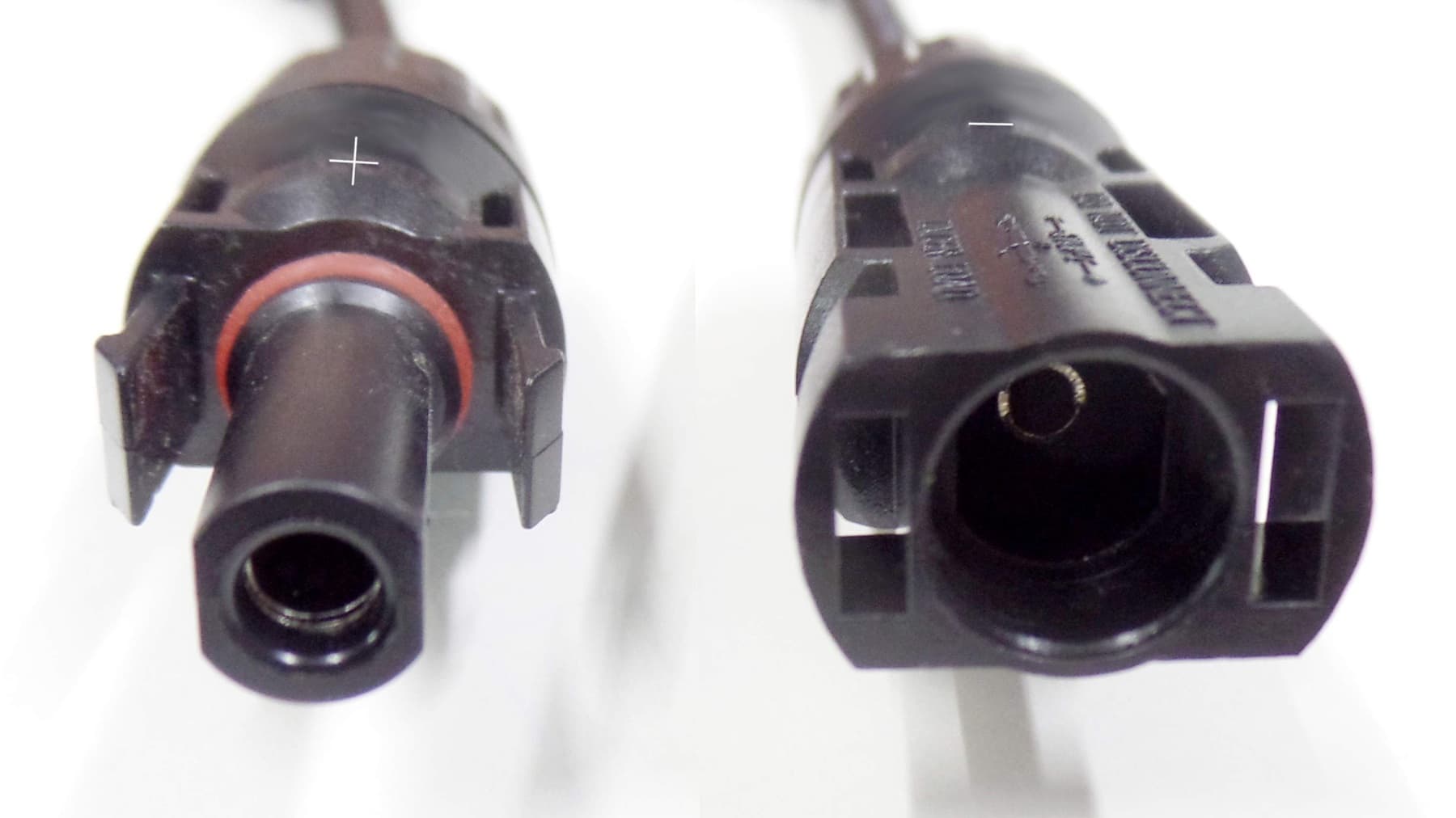 Front-view close-up of two disconnected photovoltaic connector samples showing the mating faces, locking clips and a red sealing ring
